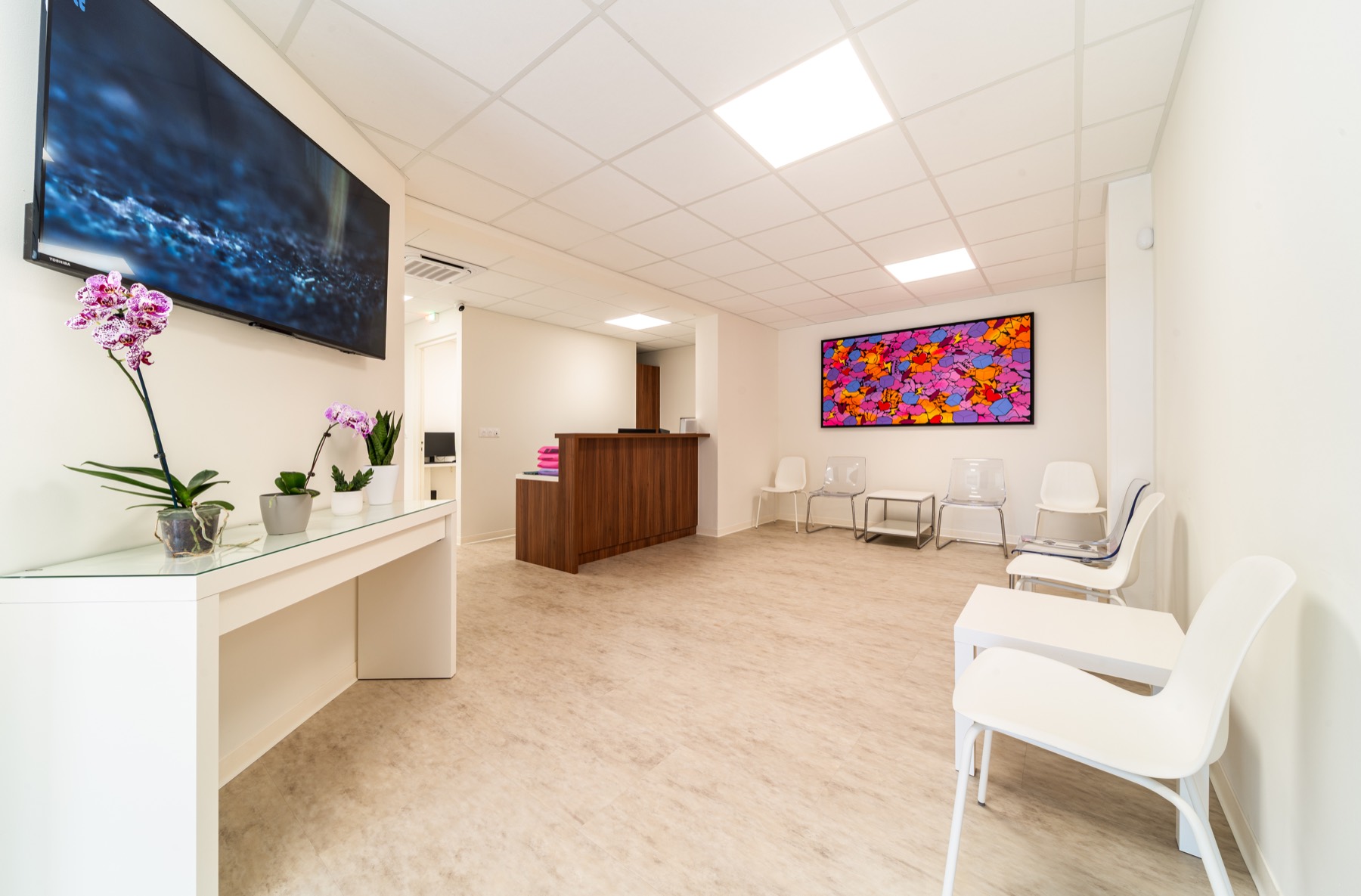 Salle d'attente du cabinet avec comptoir bois et orchidées